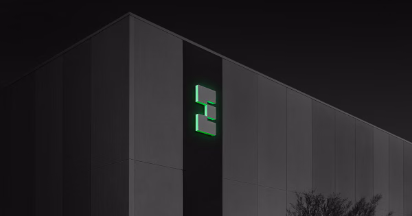 Data center building exterior at night with an illuminated green EdgeCore logo