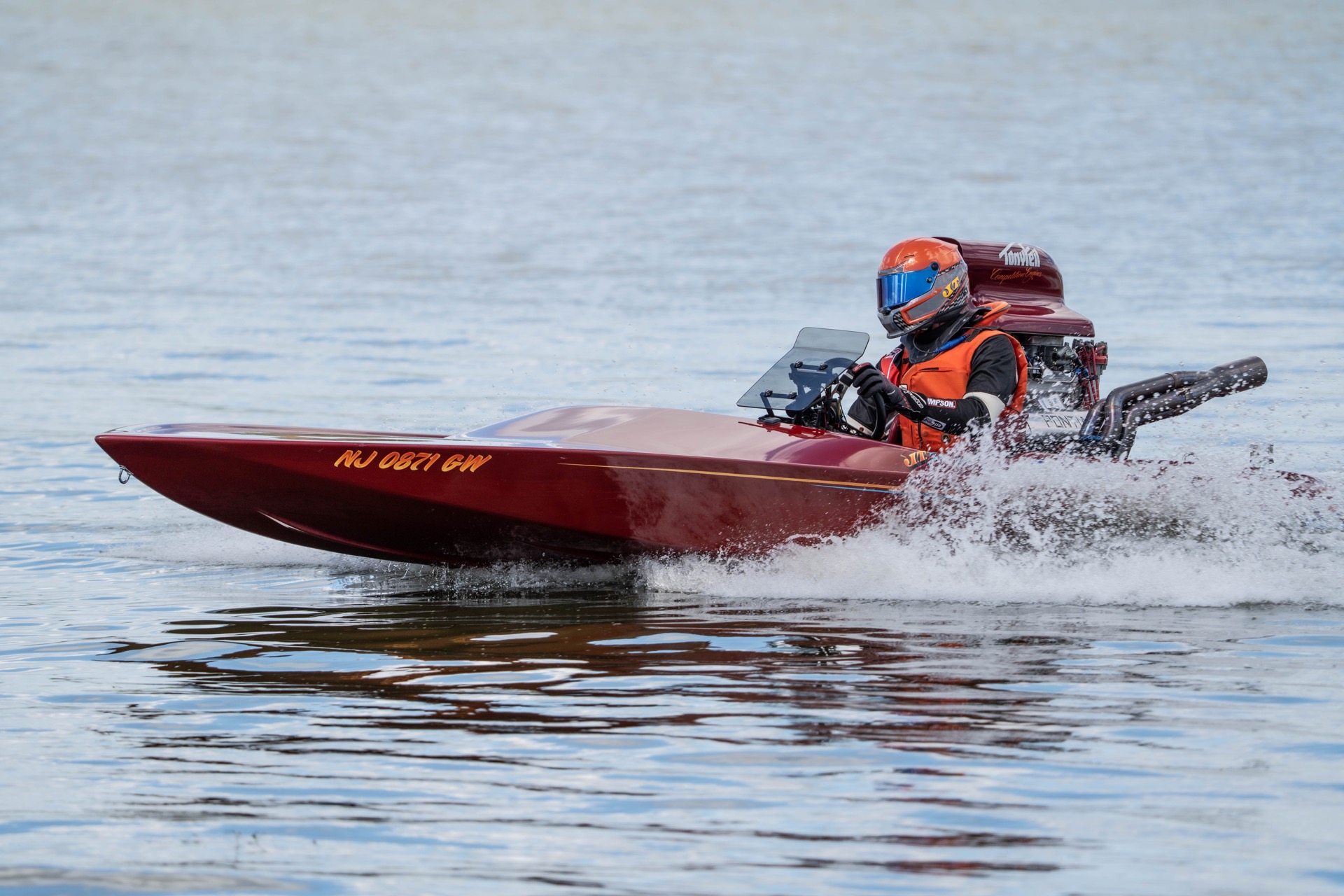 A driver in a red racing boat speeding across the water at the Orange Cup Regatta