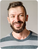 Smiling man with a beard and short styled hair wearing a striped shirt against a neutral background.