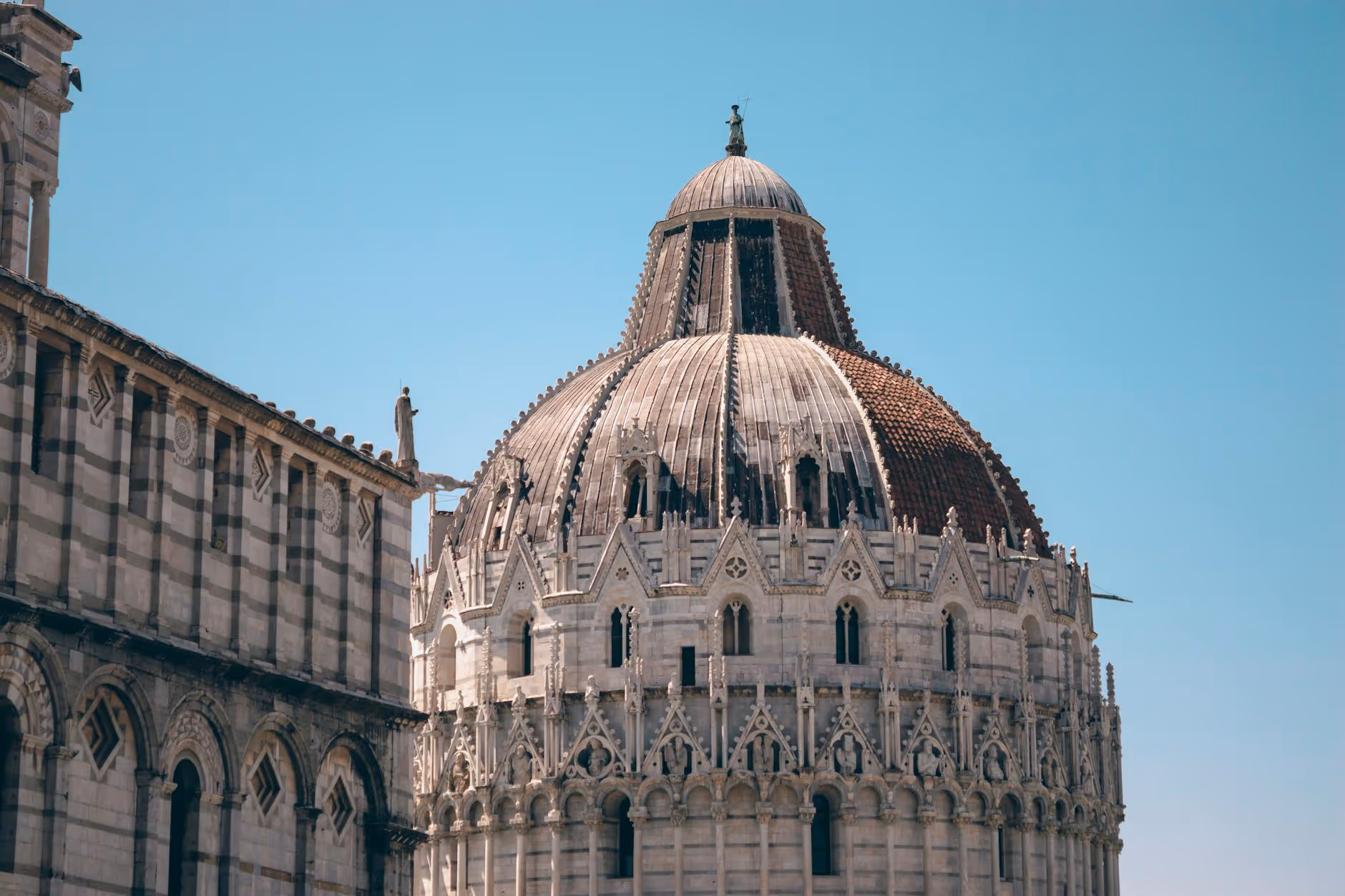 Close-up of ornate dome and gothic architectural details on a historic stone building under clear blue sky.