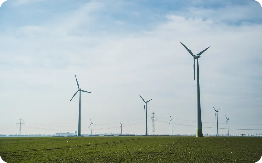Wind turbines standing in a green field under a partly cloudy sky.