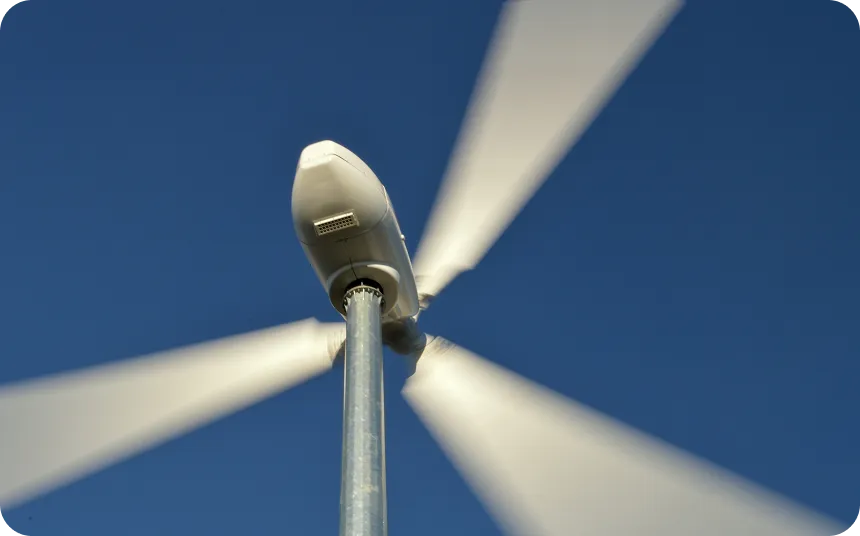 Close-up view of spinning wind turbine blades against a clear blue sky.