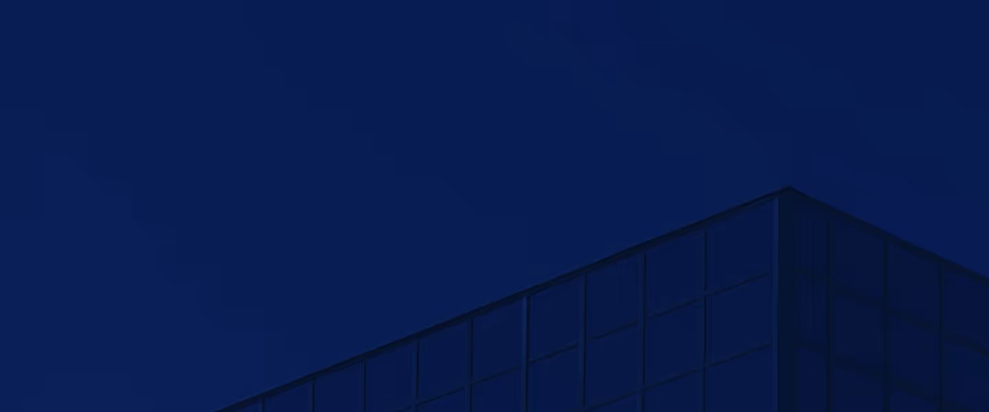 Corner of a modern glass building under a clear dark blue sky.