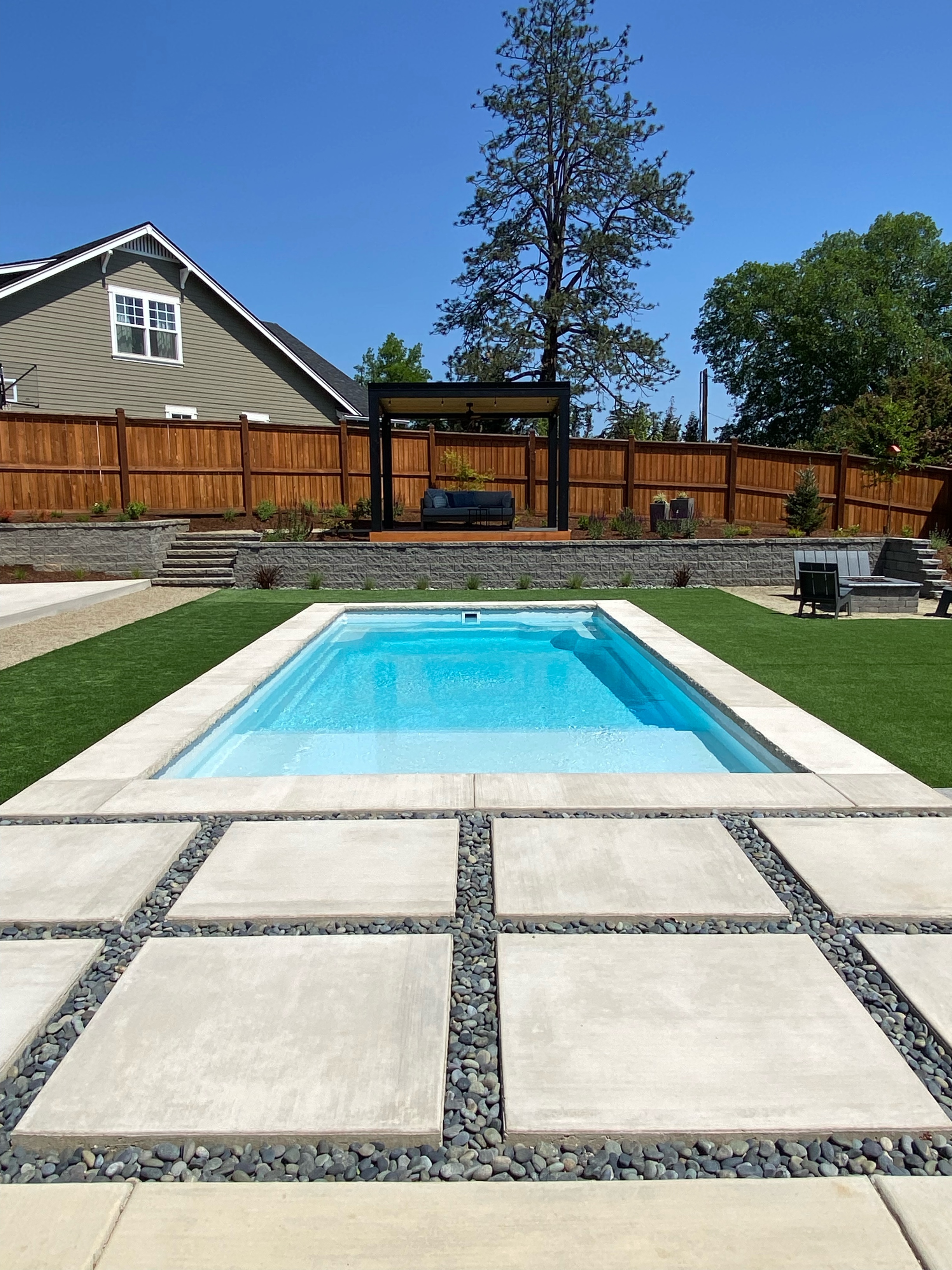 Poolside retreat with synthetic turf, retaining walls, and stone steps