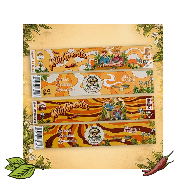 Two packs of Vêio Pimenta rolling papers, one in white paper and the other in brown paper, featuring illustrations of two men with hats, chili peppers, and green plants on a yellow and orange background with natural and sustainable claims.