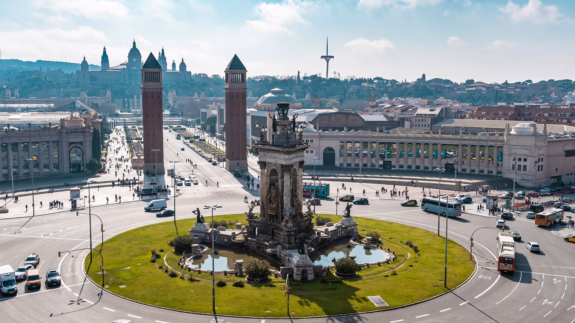 Barcelona's Placa de Catalunya with central fountain, twin brick towers, and surrounding traffic