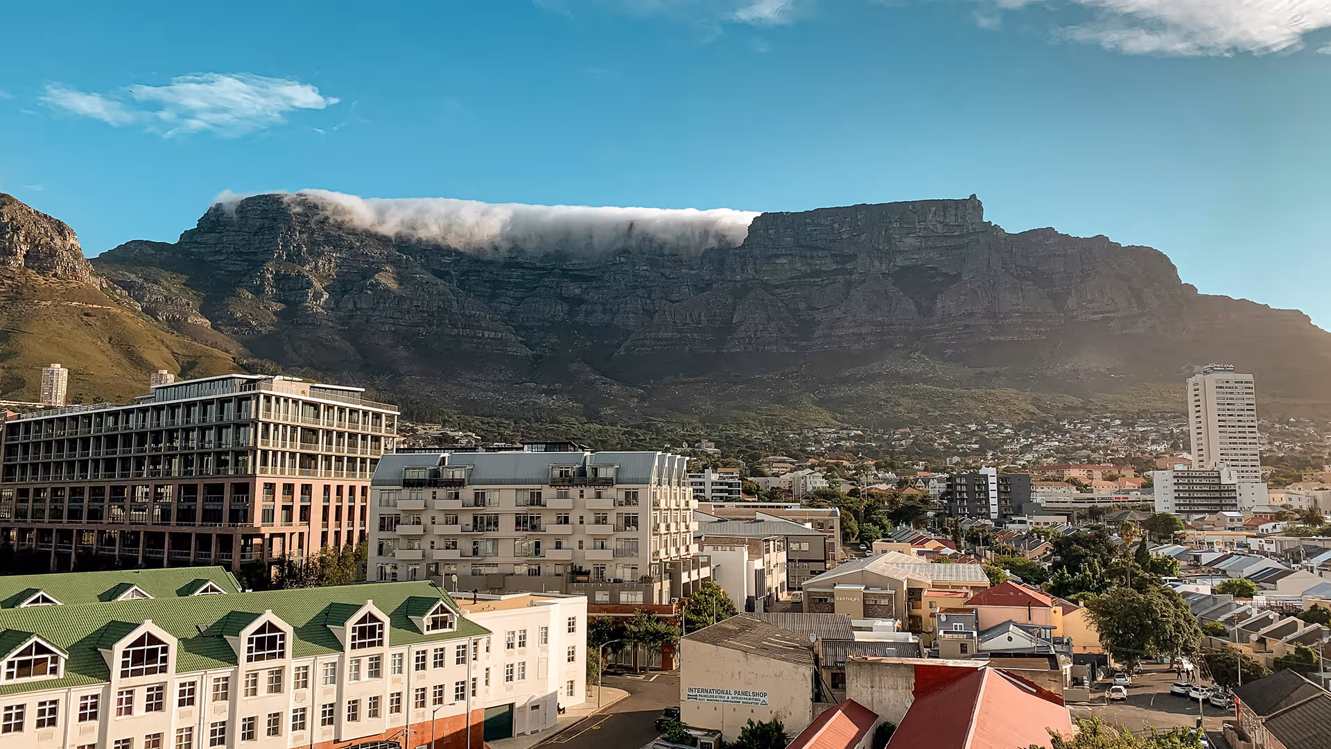  Cape Town cityscape with Table Mountain under clouds, colorful rooftops, and high-rise buildings