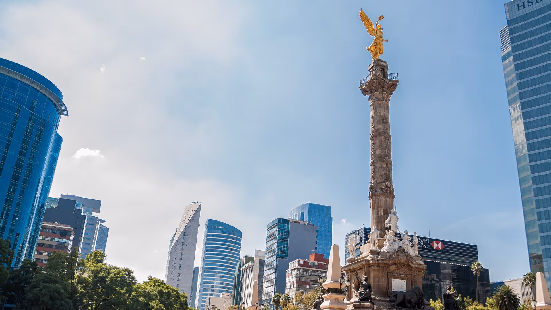 Mexico City’s Angel of Independence column with golden statue surrounded by modern glass skyscrapers