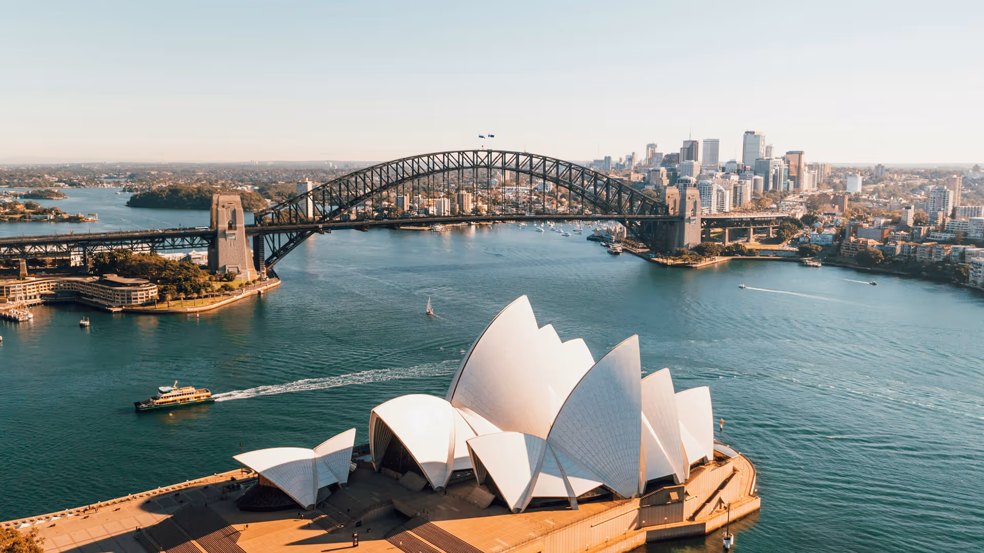 Sydney Harbour with Opera House sails, Harbour Bridge, and city skyline over blue water
