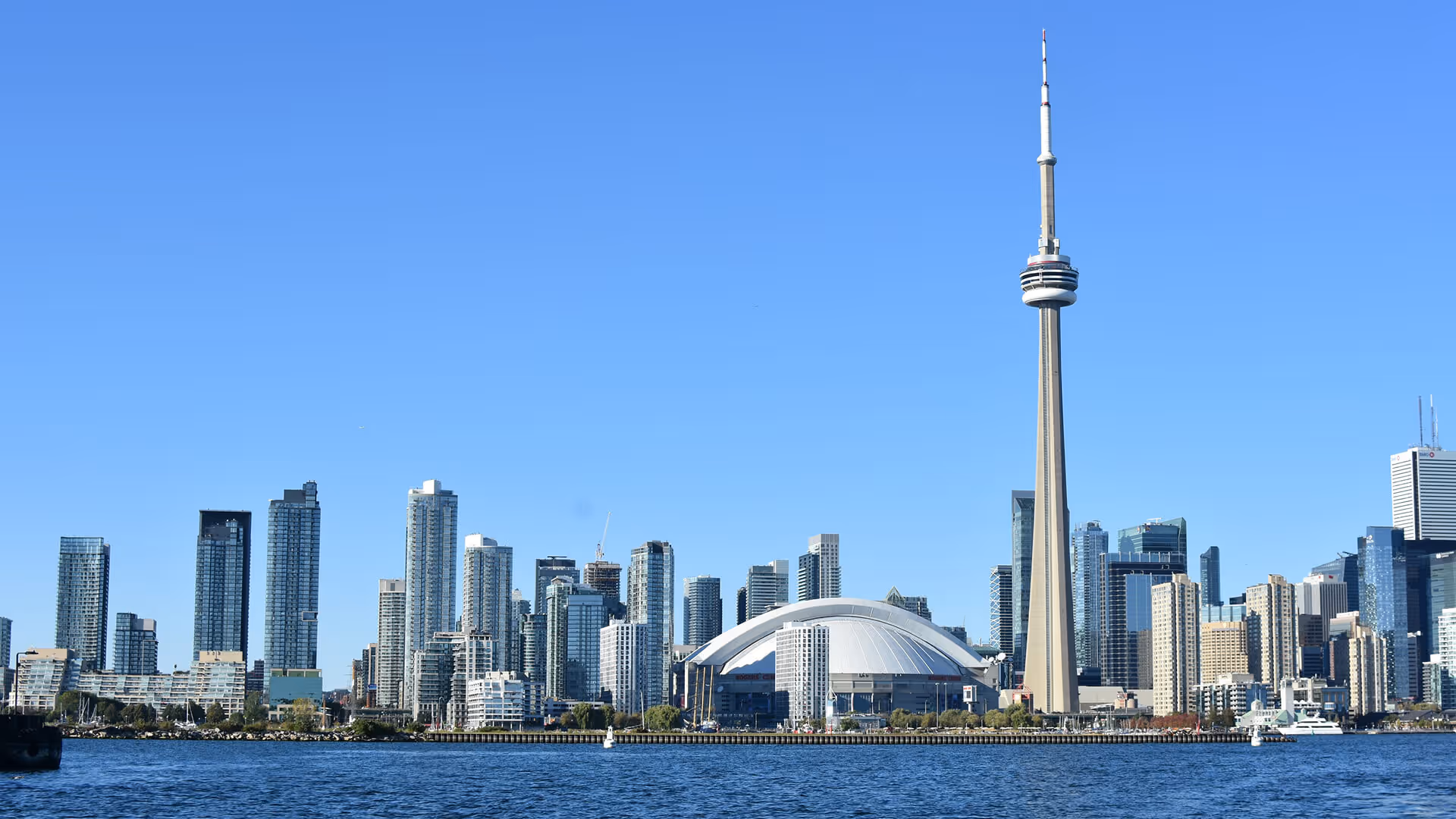 Toronto skyline featuring CN Tower spire, Rogers Centre dome, high-rises, and Lake Ontario