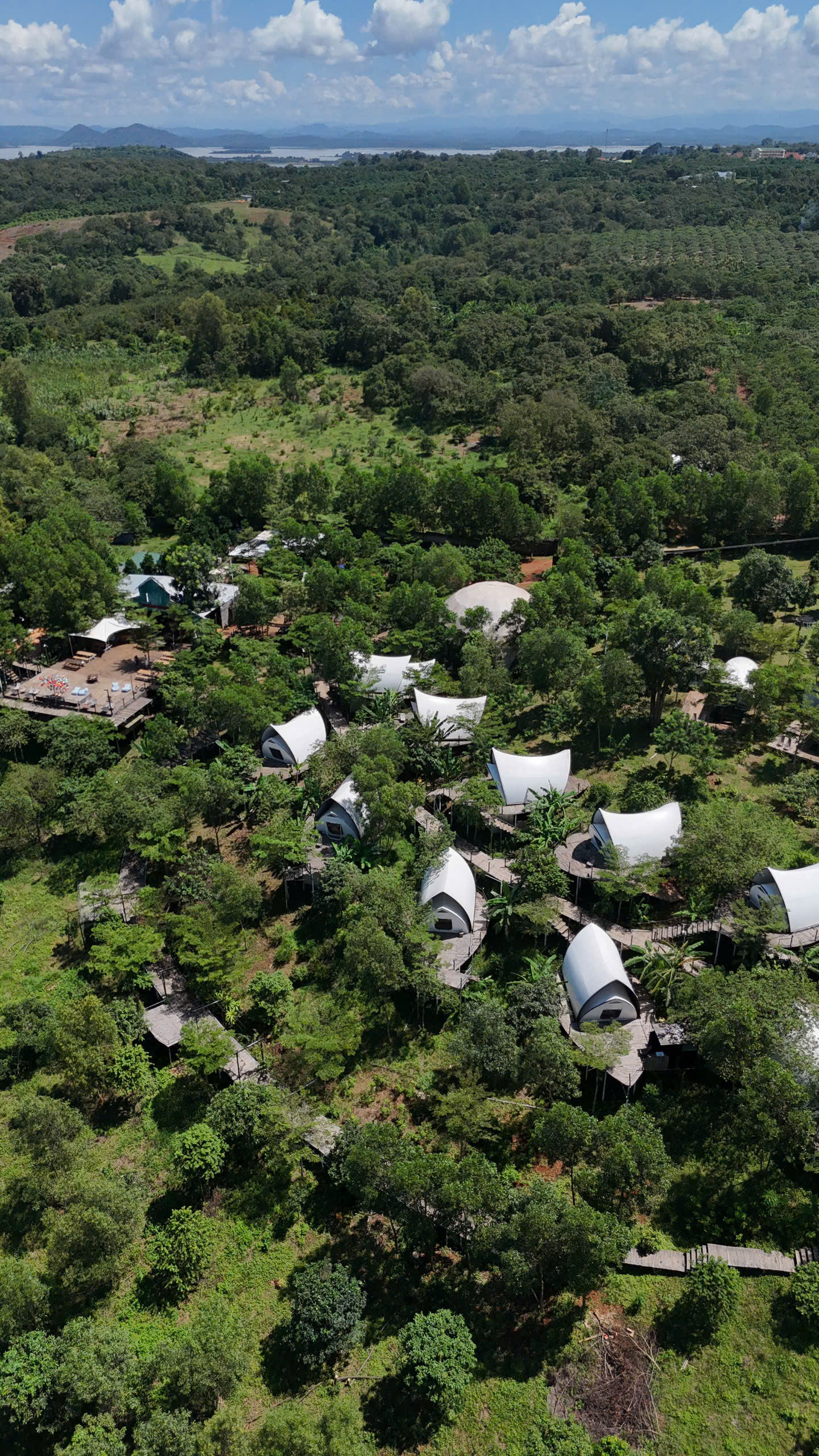 Toàn cảnh Panorama Glamping bên hồ Trị An – khu glamping giữa đồi xanh với những mái lều trắng nổi bật. Từ trên cao nhìn xuống, cả khu như hòa vào thiên nhiên, nơi mỗi lều đều có tầm nhìn riêng ra mặt hồ và đón trọn nắng gió trong lành.