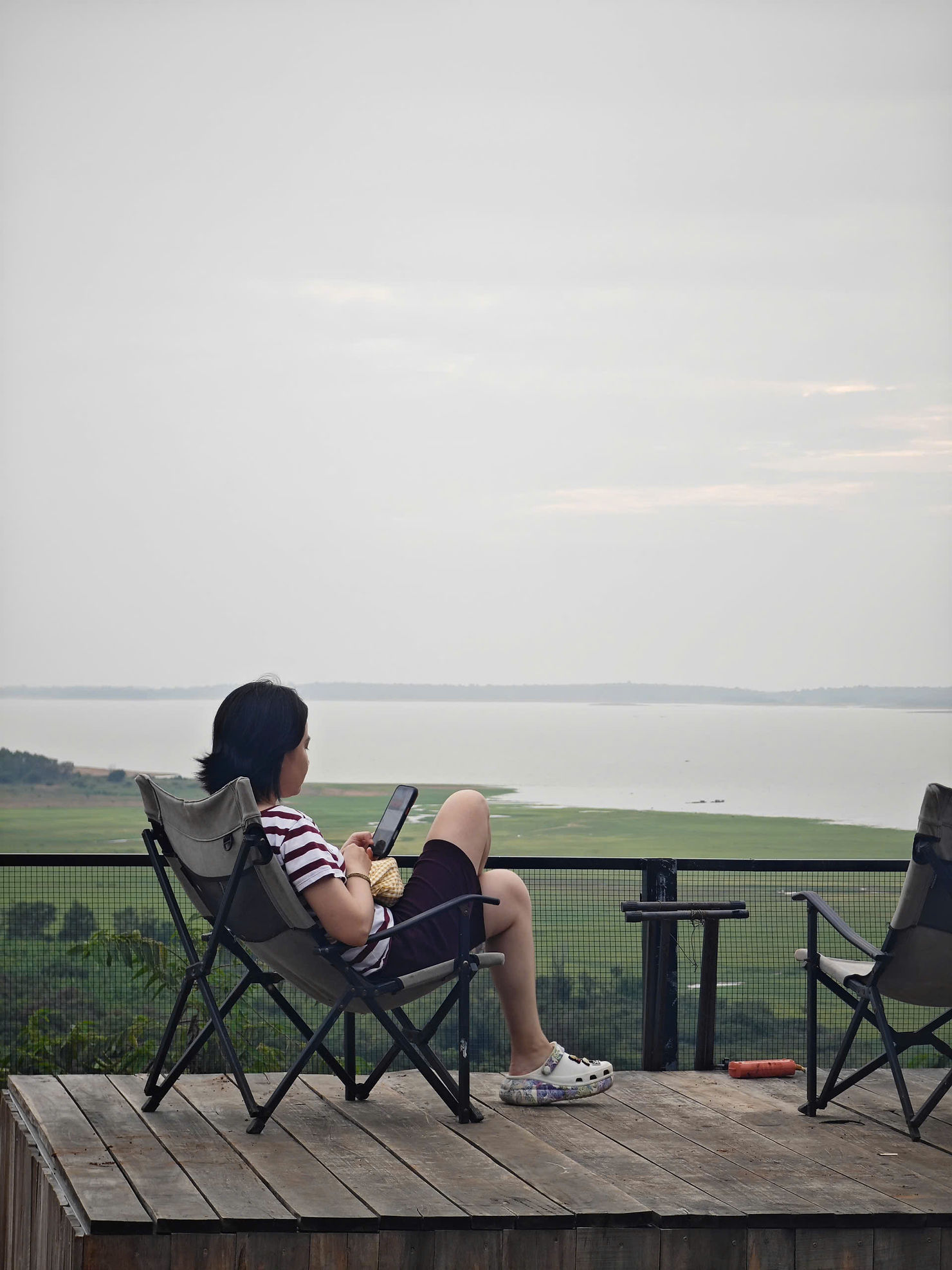 Khoảnh khắc thư giãn tại Panorama Glamping Hồ Trị An – ngồi bên ban công gỗ, thả hồn theo mặt hồ xanh thẳm, tận hưởng không gian glamping gần Sài Gòn để chống burnout và tìm lại cân bằng.