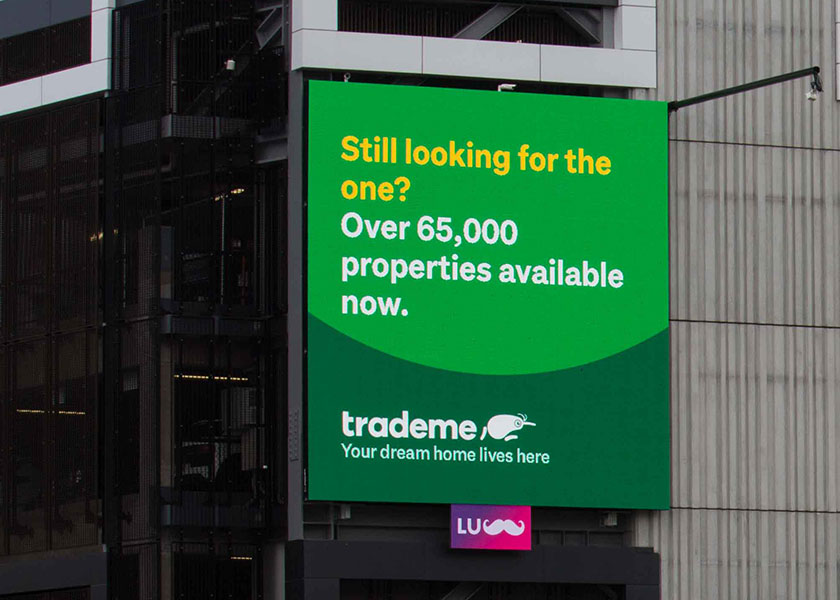 Outdoor billboard advertising Trade Me properties with text: 'Still looking for the one? Over 65,000 properties available now.'