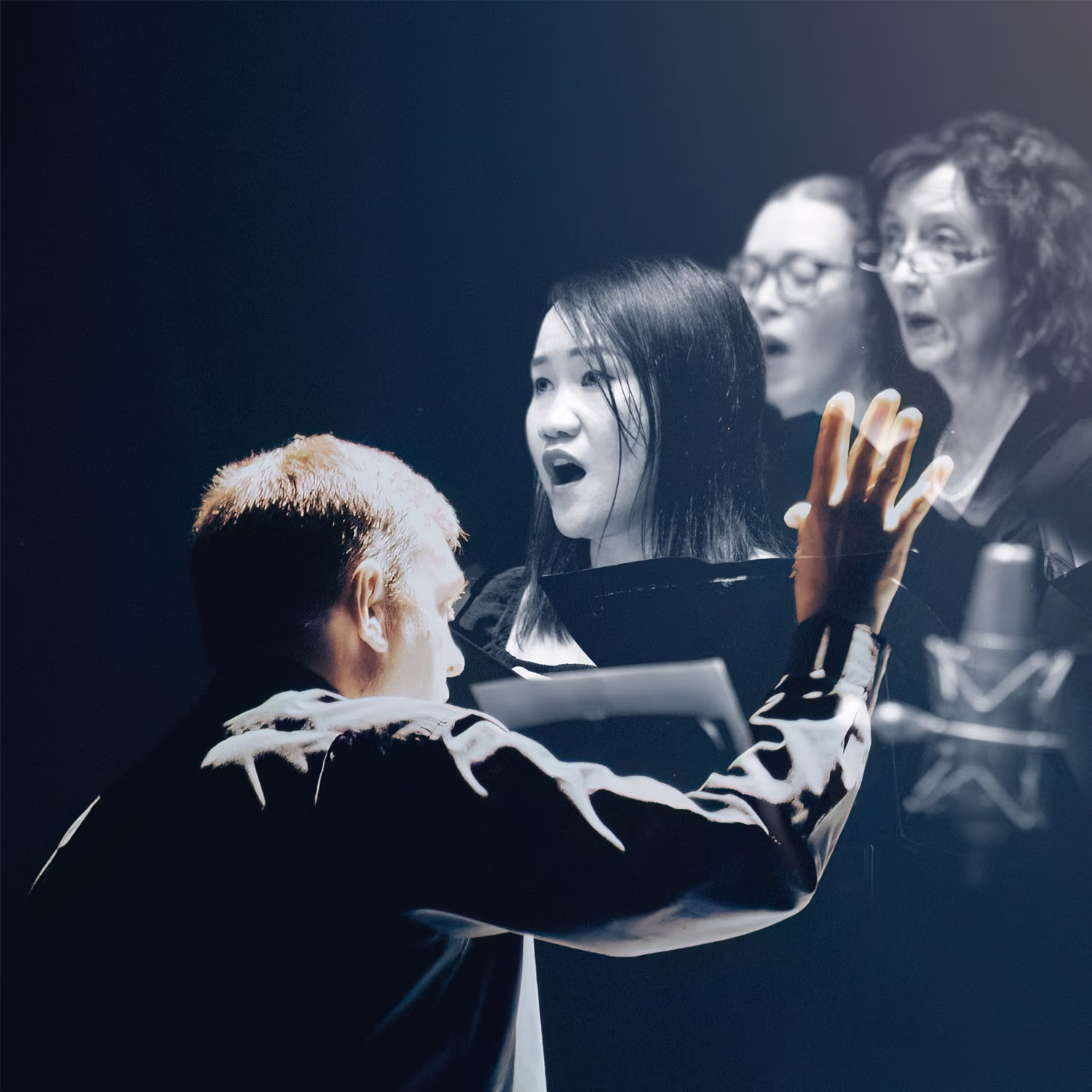 A conductor leads a choir of four singers, seen from behind with one hand raised and a baton in the other. The singers, arranged in a semi-circle, are captured mid-performance with open mouths. A dark background emphasizes their focused expressions