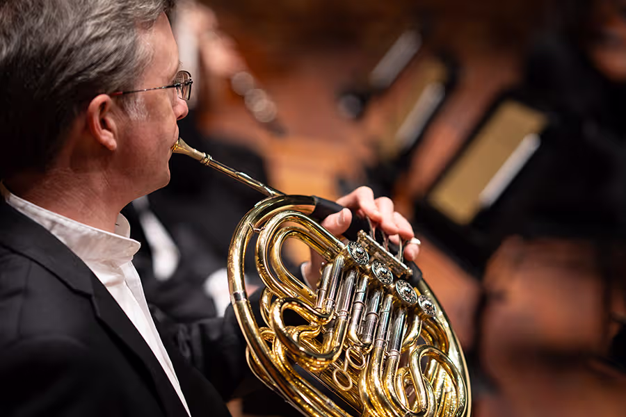 A horn player performing on stage.