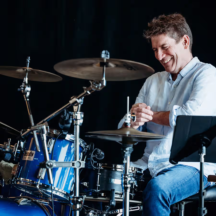 A smiling man sitting at a drum kit. 