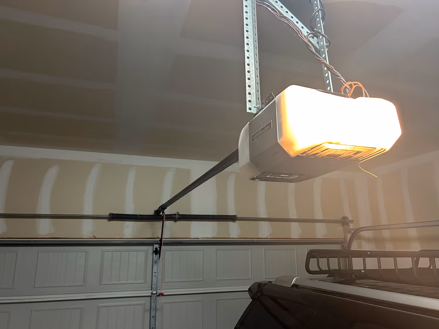 LiftMaster garage door opener installed on a ceiling with partially visible vehicle roof and garage door in the background.