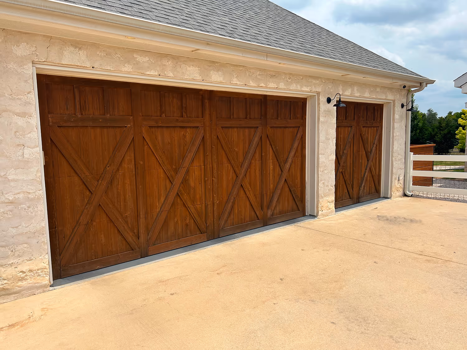 Stone exterior garage with two wooden barn-style doors on a concrete driveway.