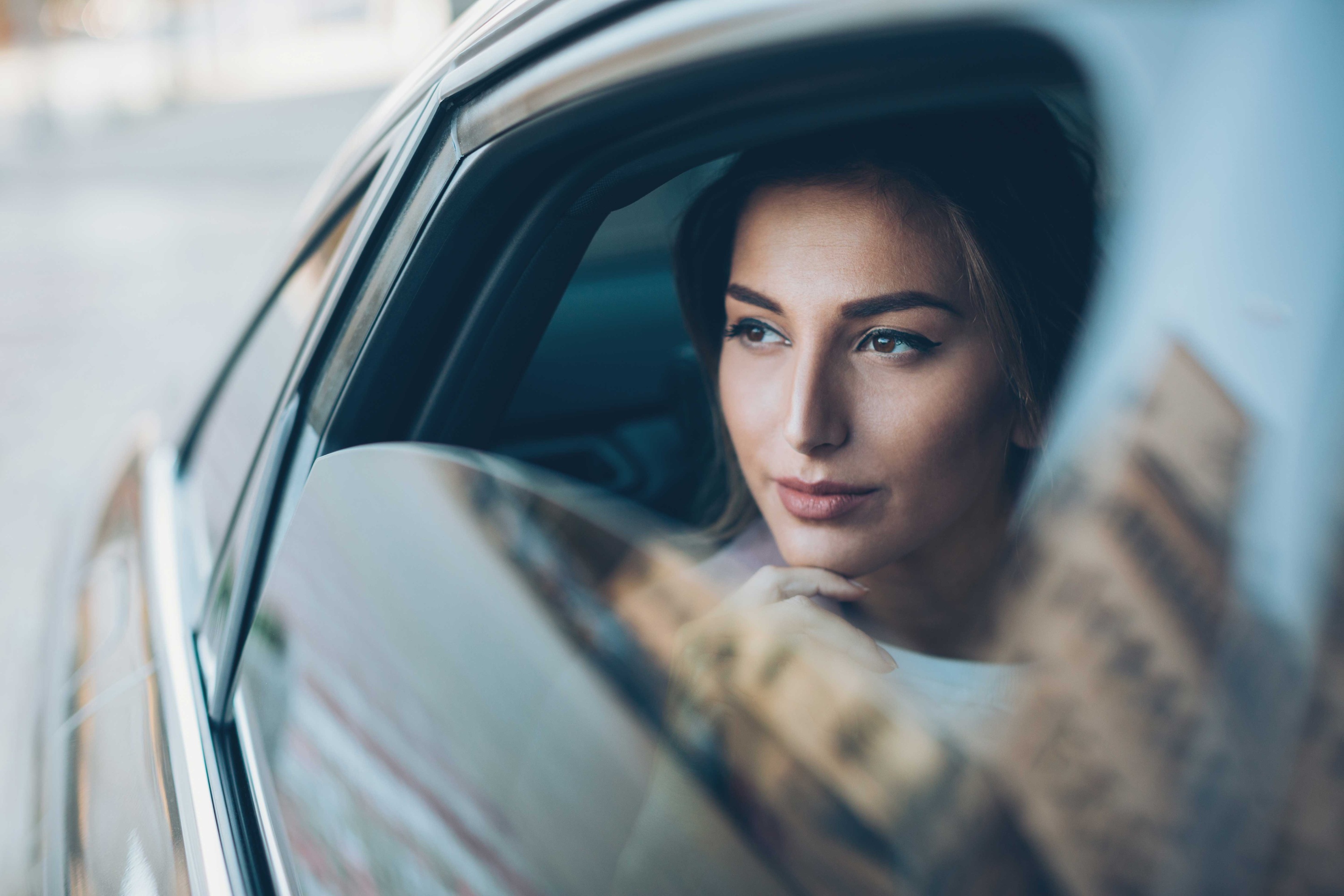 Femme regardant par la fenêtre d'un véhicule de luxe conduit par quelqu'un d'autre