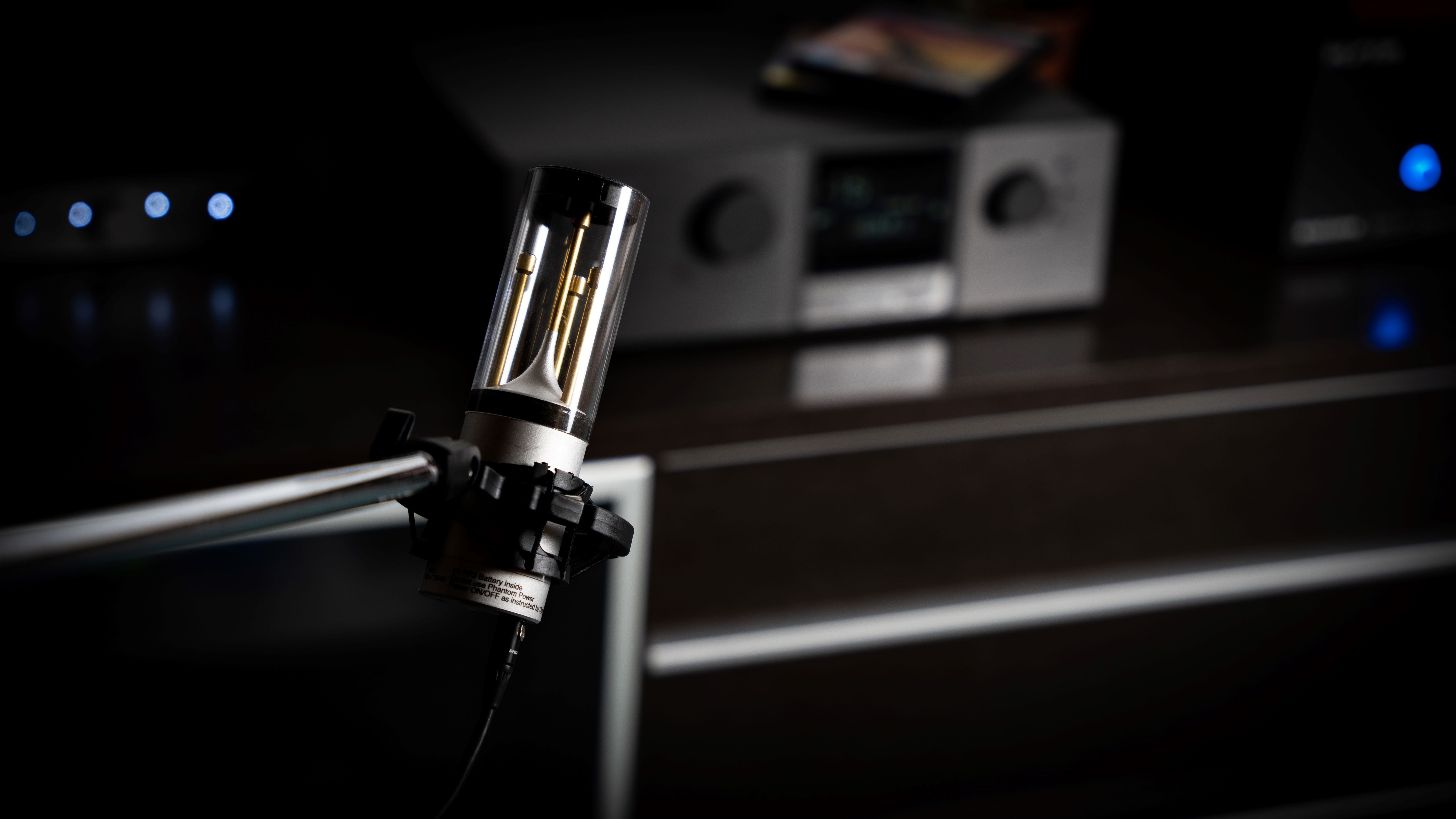 A Trinnov microphone in a home theatre with a Trinnov amplifier in the background