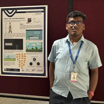 Young man with glasses and ID badge standing next to a V-Smart graduation capstone project poster.
