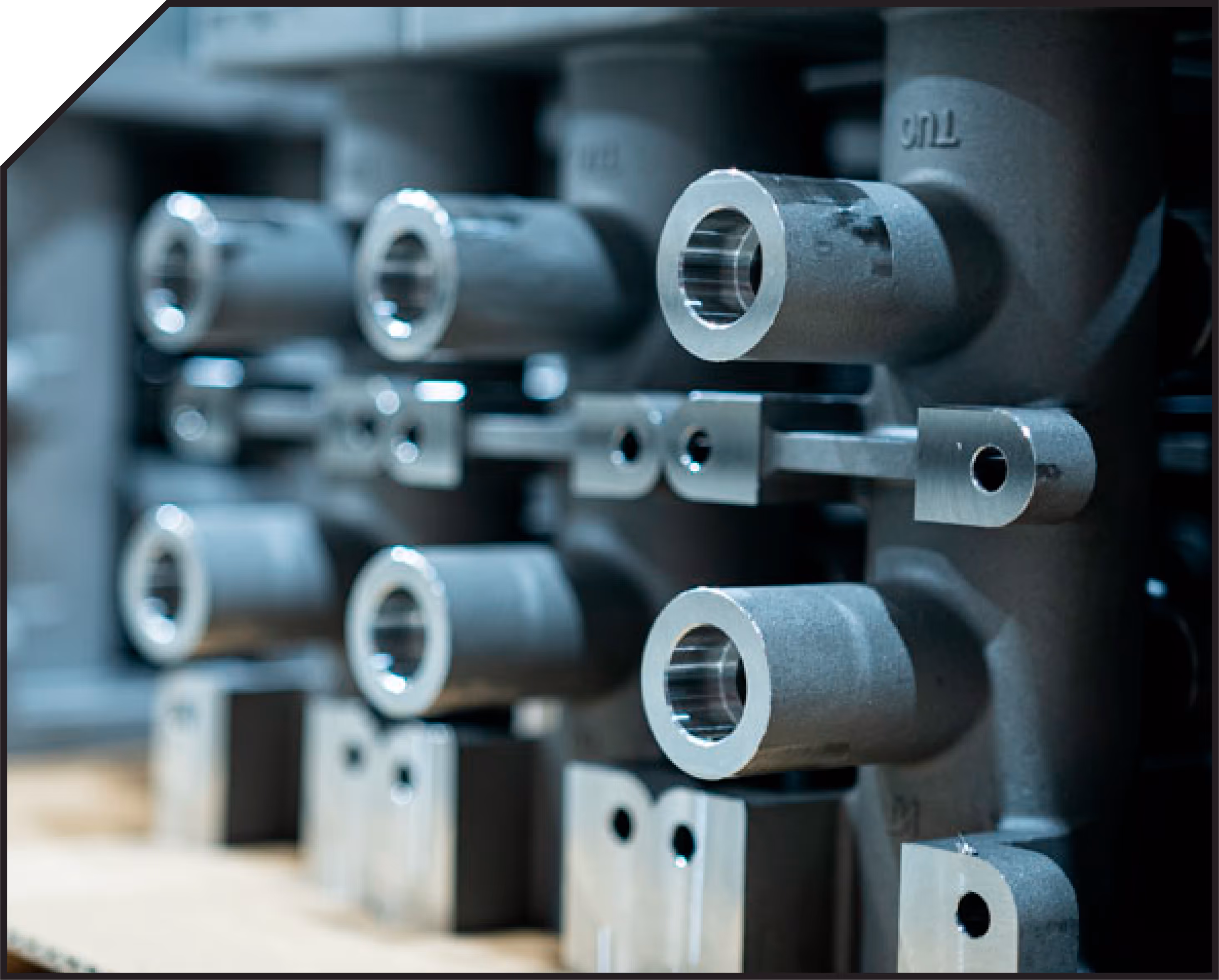 Close-up of metal mechanical parts with cylindrical openings arranged in a row on a shelf.
