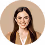 Smiling woman with long brown hair wearing a white top and beige blazer against a light background.
