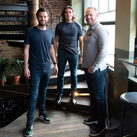 Two coworkers, a woman and a man, looking at a smartphone together in a modern office setting.