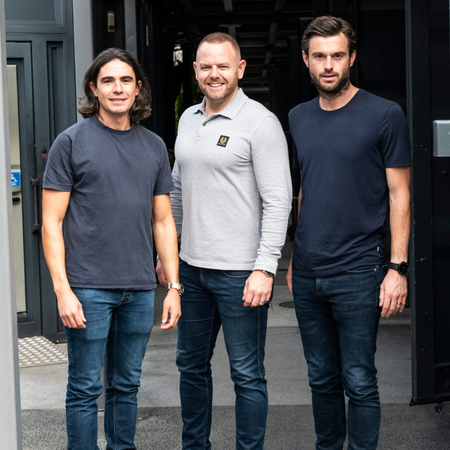 Nurse in green scrubs measuring blood pressure of a seated middle-aged woman with a cuff on her arm.