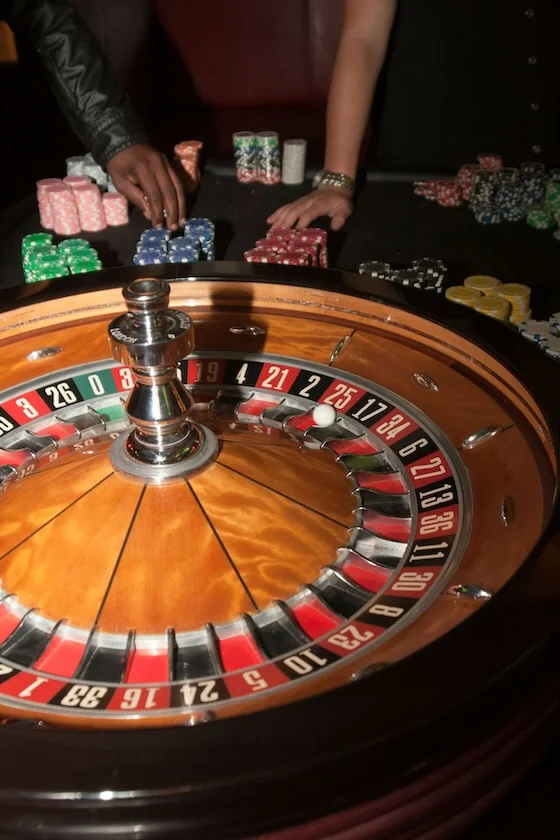 Casino roulette wheel with players placing chip bets