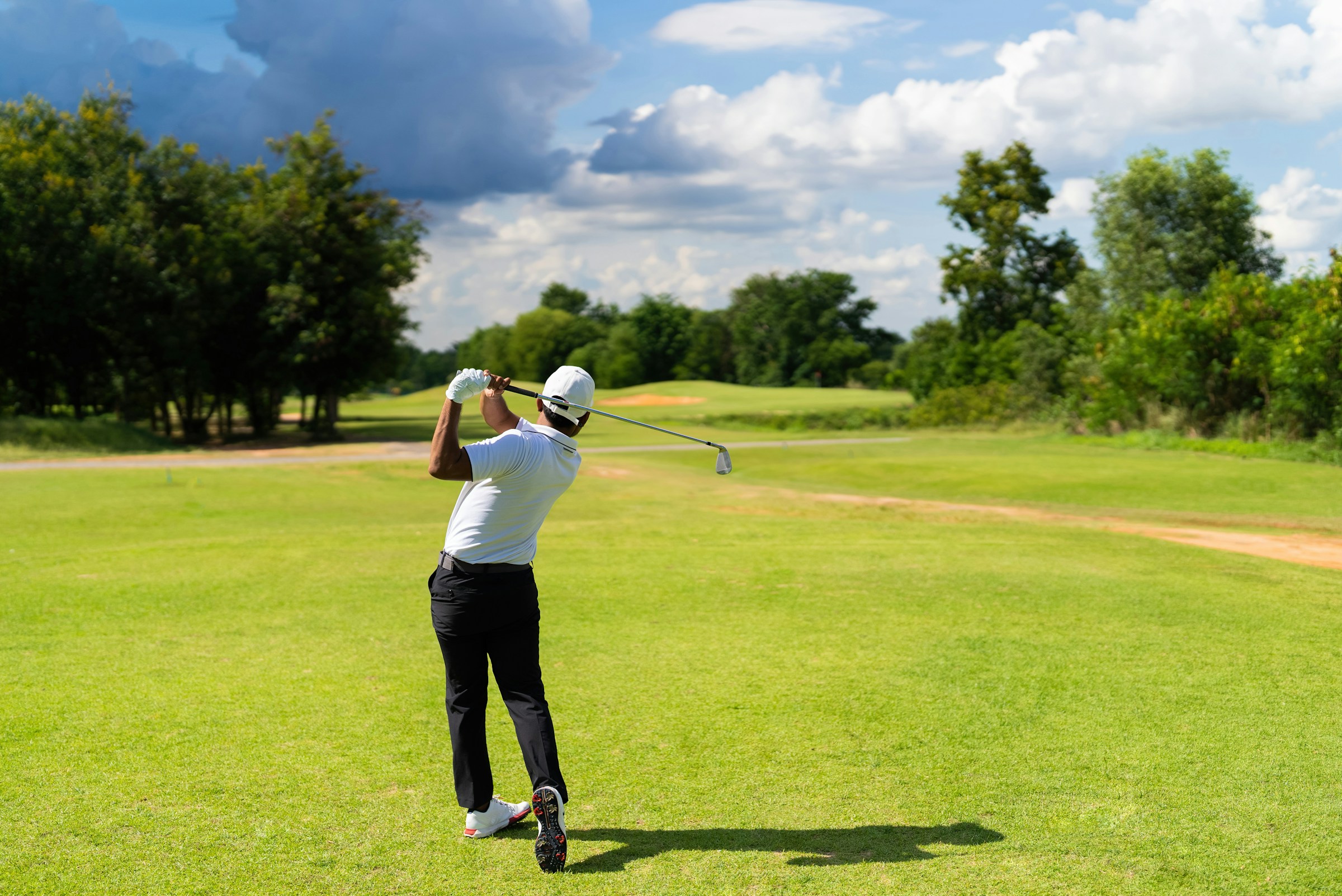 Golfer completing a swing on a fairway