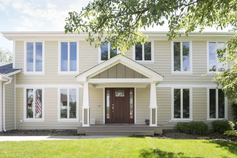 Tan siding home with a craftsman front entry and new door