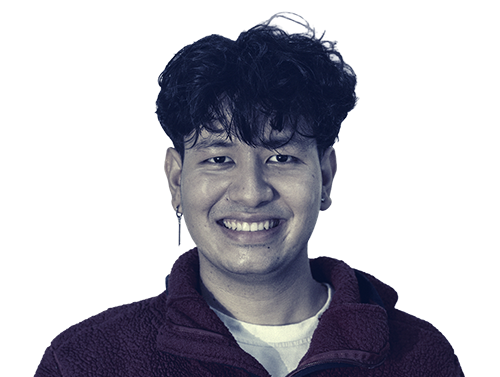 Young man with curly hair smiling, wearing a maroon fleece jacket and white shirt.