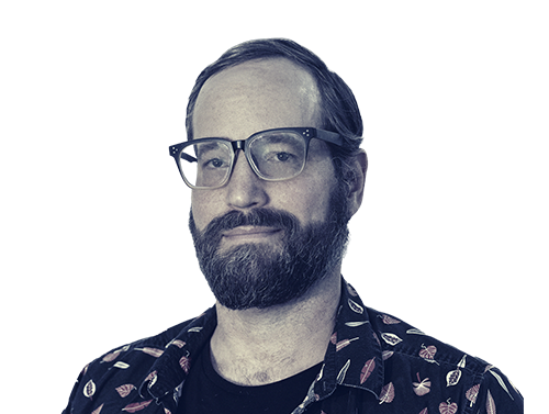 Man with a beard and glasses wearing a dark shirt with a floral pattern.