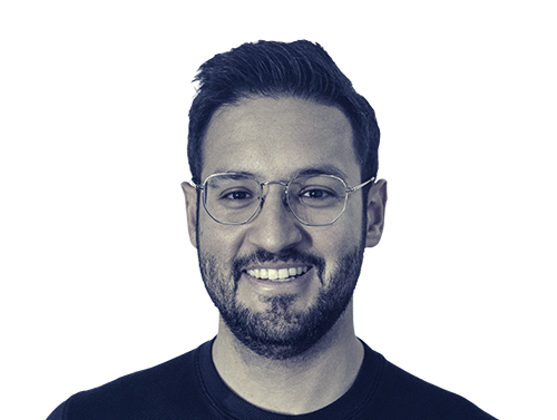 Smiling man with glasses, short dark hair, and a trimmed beard wearing a dark shirt.