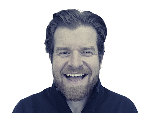 Smiling man with beard and dark hair wearing a dark zip-up jacket.