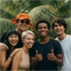 A small thumbnail-sized group photo of five smiling friends in a tropical outdoor setting.