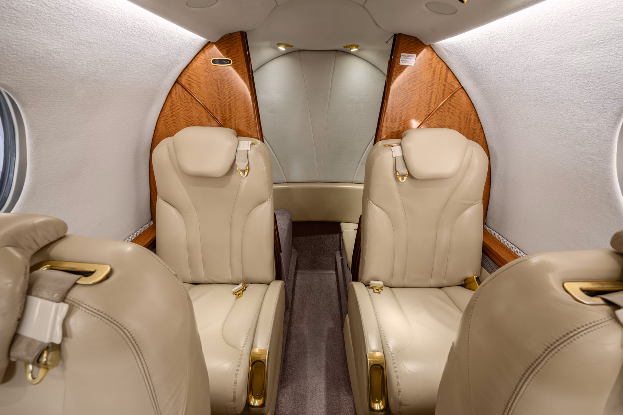 Luxurious private jet interior with four gray leather seats, a fold-out table, and multiple cabin windows.
