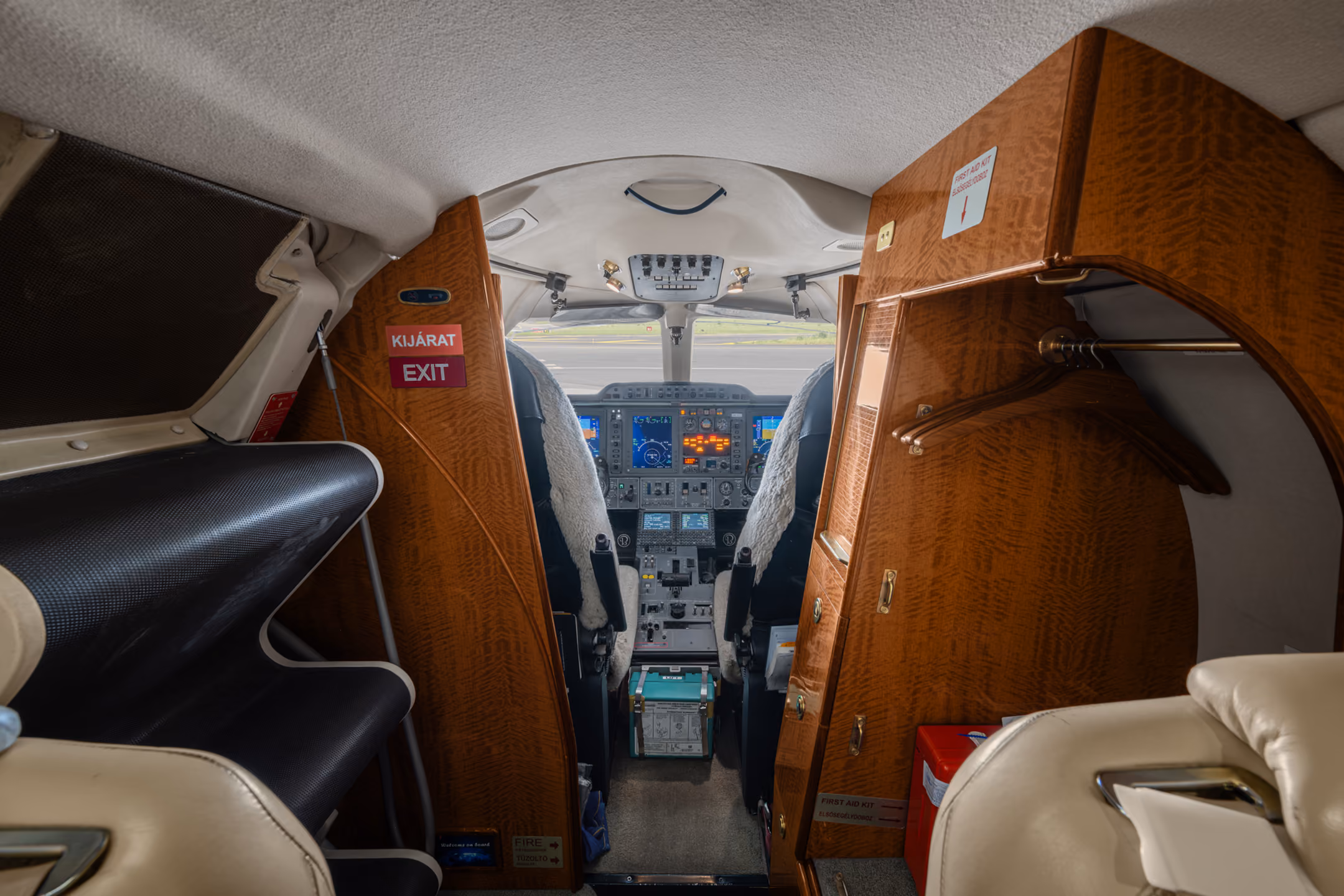 Interior of a private jet cabin with six gray leather seats arranged in pairs and windows on both sides.