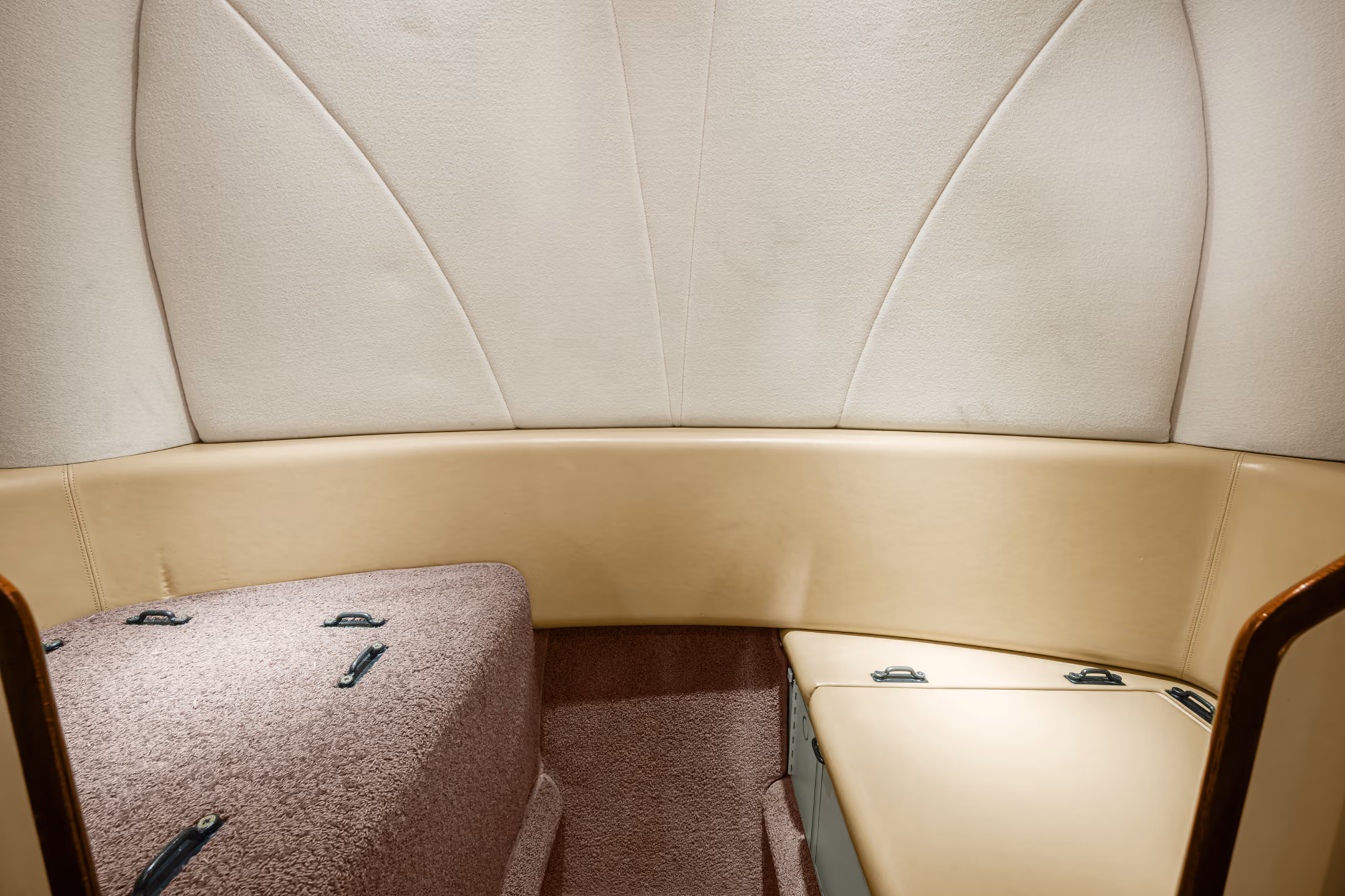 Interior of a private jet with gray leather seats, fold-out table, and five windows showing a blue sky.