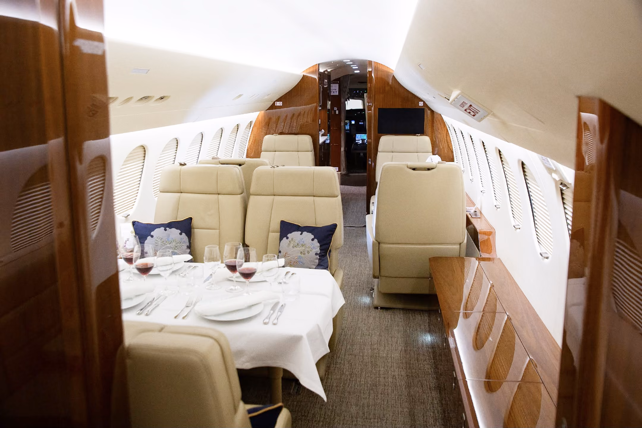 Interior of a private jet with gray leather seats and a storage cabinet holding a basket of snacks between the seats.