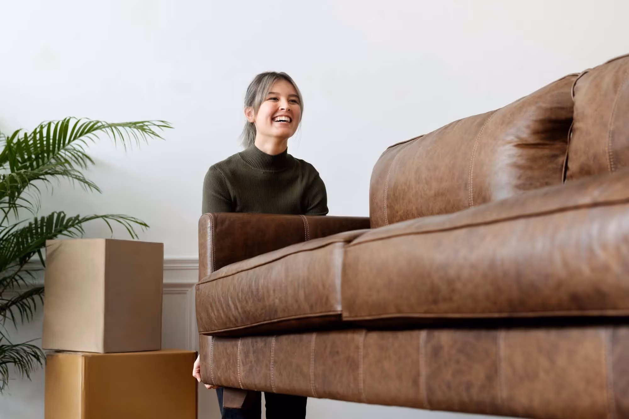 A woman lifting one end of a sofa during a house move