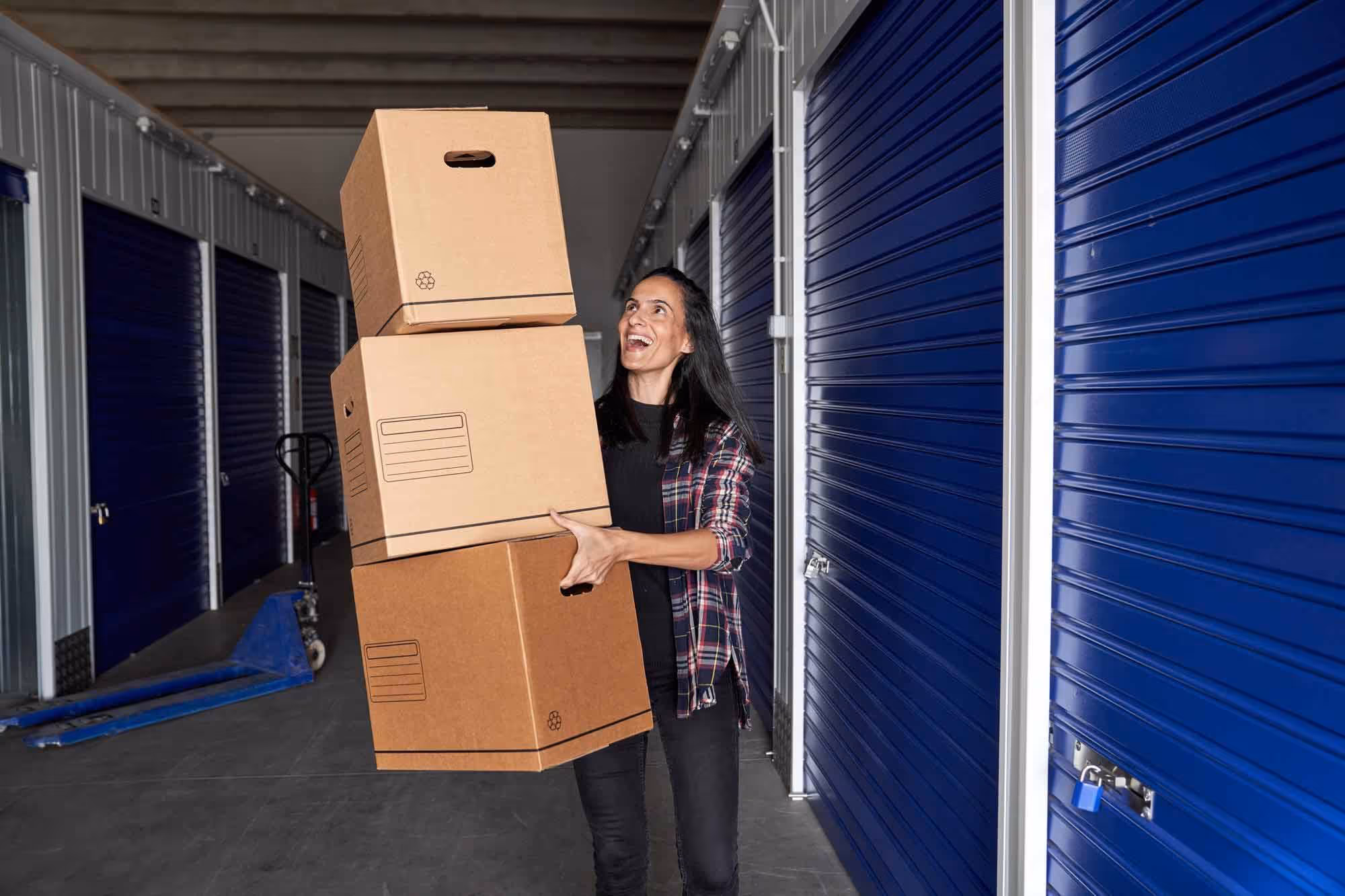 A woman carrying several boxes outside a self-storage unit
