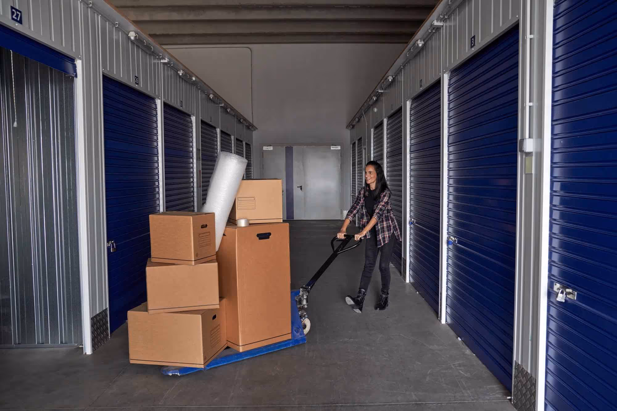 A woman with boxes on a trolley at a self-storage unit