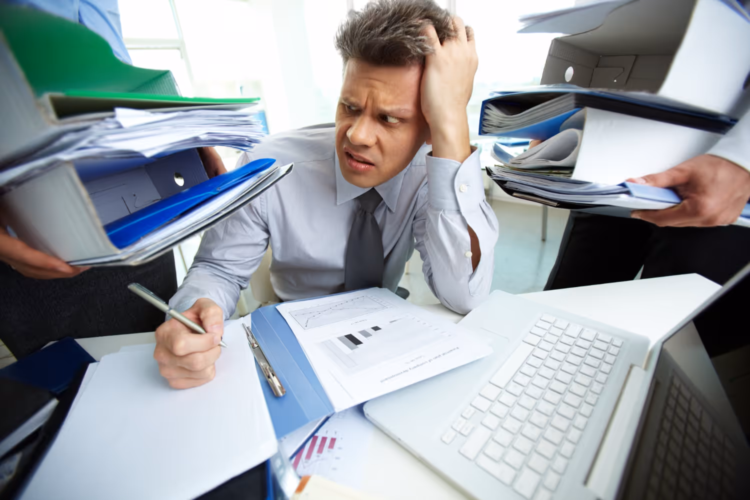A man at a desk surrounded by files and office paperwork