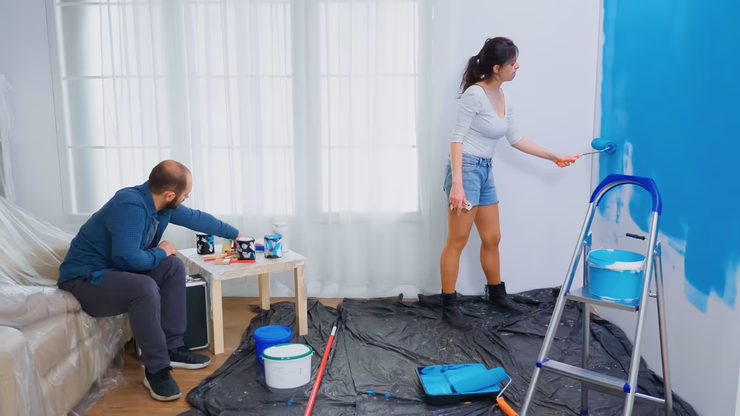 A couple decorating their living room at home