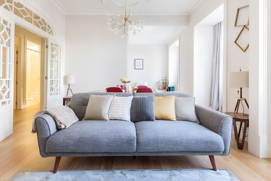 Bright living room with blue sofa and dining area in a Lisbon apartment