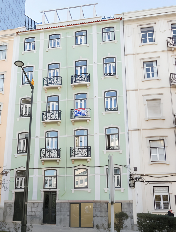 Exterior of a traditional Lisbon apartment building with green facade and balconies