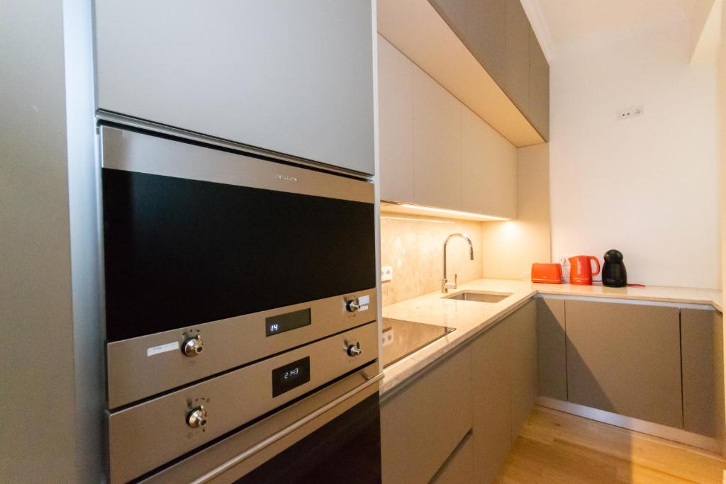 Modern kitchen with built-in stainless steel oven, beige cabinets, countertop, sink, toaster, and kettle.