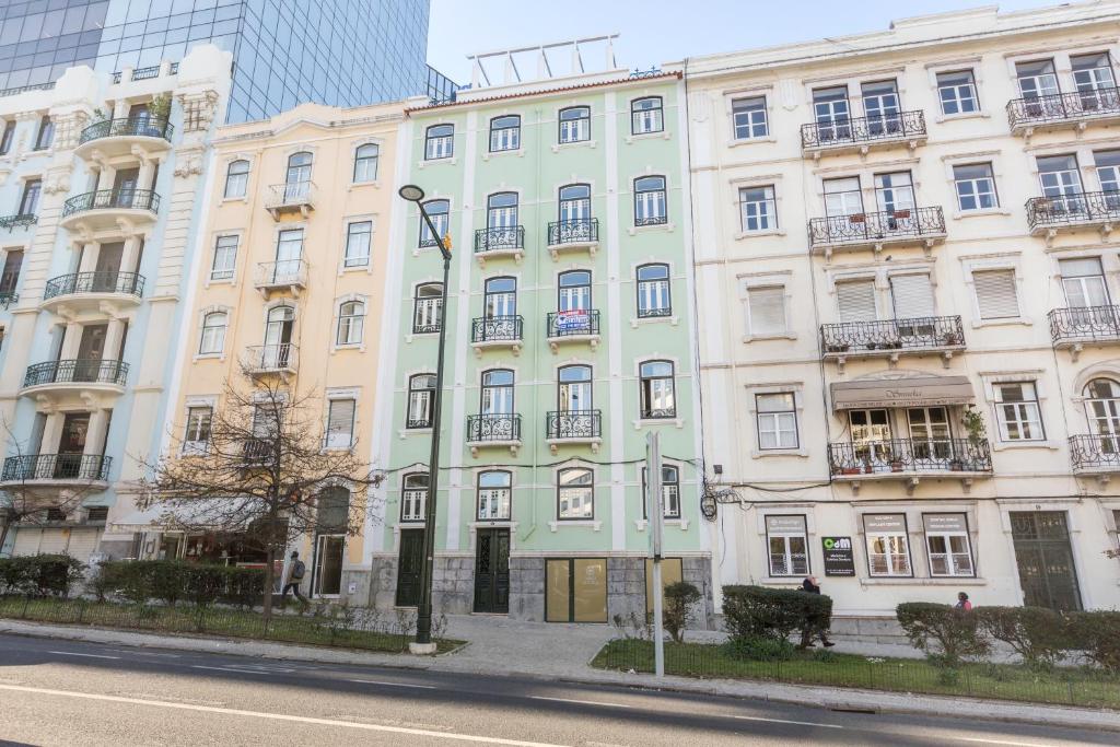 Row of pastel-colored multi-story buildings with balconies along a sidewalk and street.